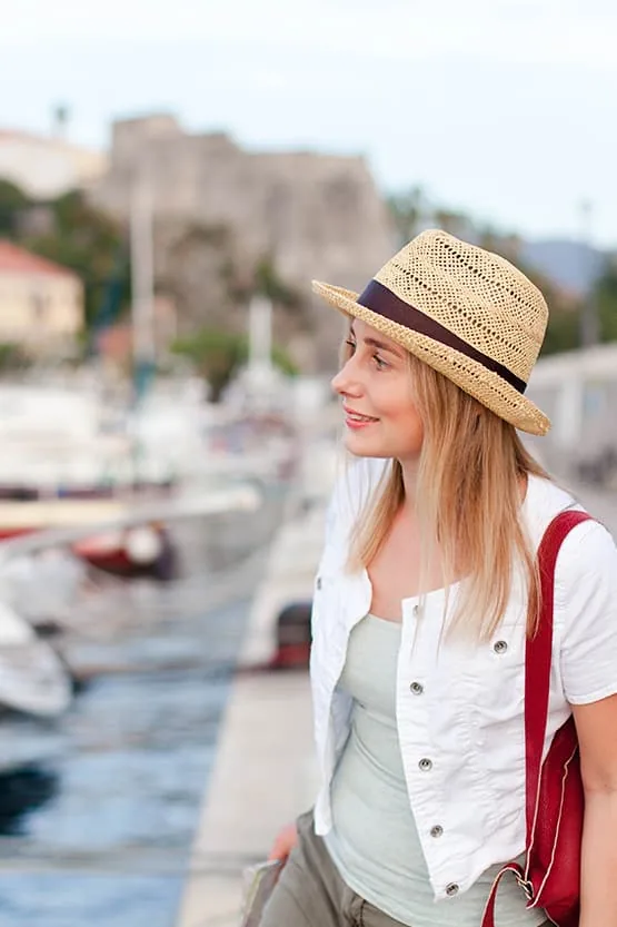 Touriste en chapeau près des bateaux d’un port de plaisance