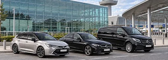 Berline et van VTC stationnés devant un terminal d’aéroport